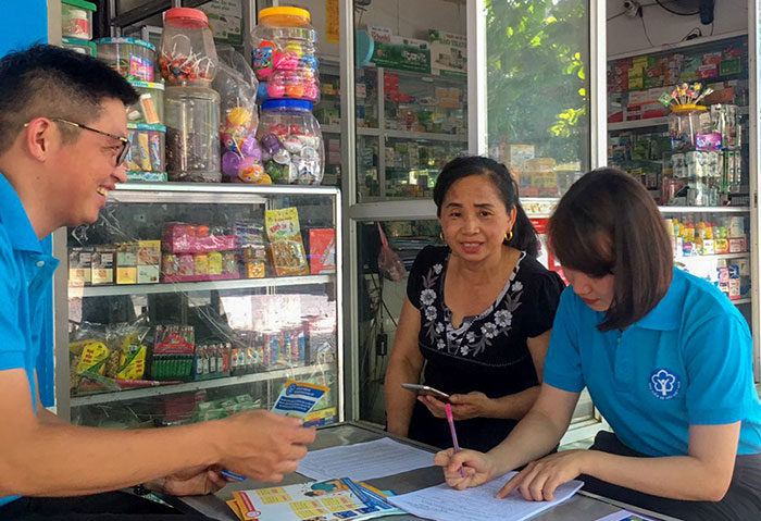 Cán bộ BHXH, Bưu điện huyện Tuần Giáo tuyên truyền về BHXH tự nguyện đến người dân thị trấn Tuần Giáo. Ảnh: Diệp Chi